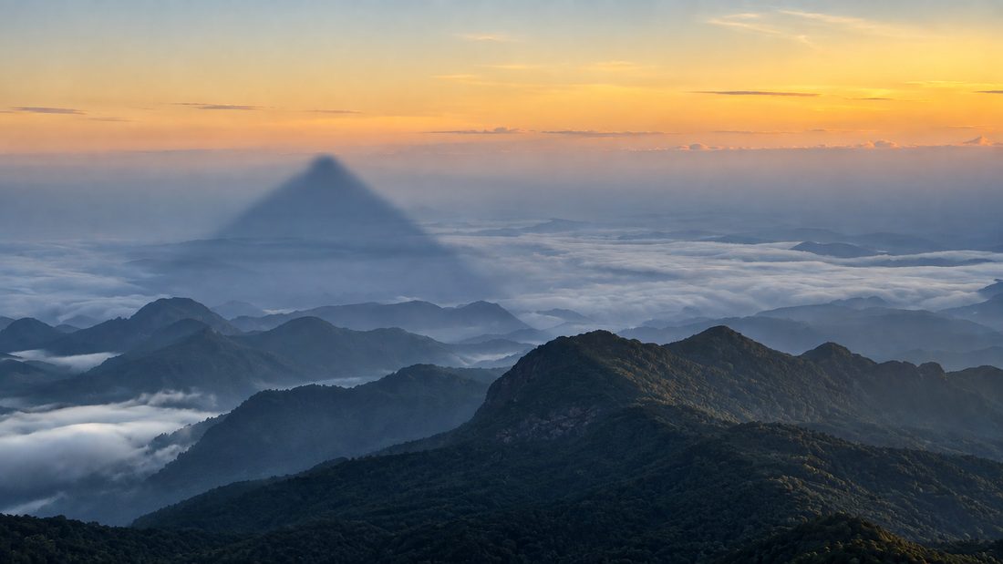 The triangular shadow of Adam's Peak cast across cloud at dawn, Sri Lanka