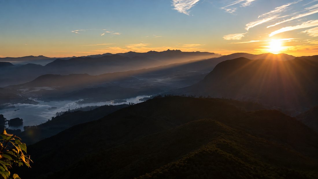 Sunrise breaking over misty ridges from the summit of Adam's Peak, Sri Lanka