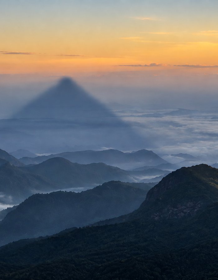 The triangular shadow of Adam’s Peak cast across the clouds at dawn