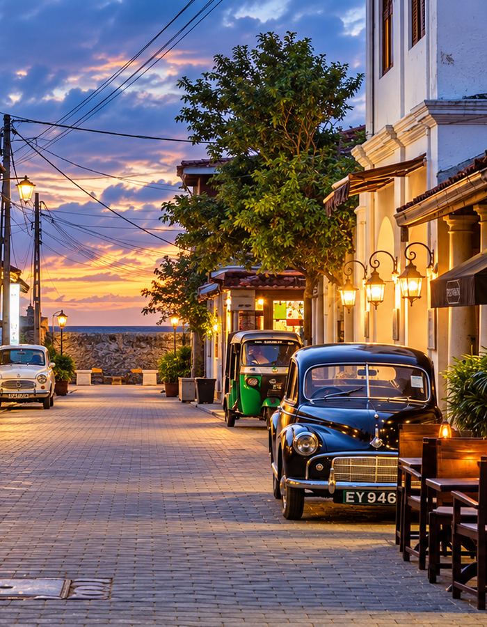A lamplit Galle Fort street at golden hour looking towards the ramparts
