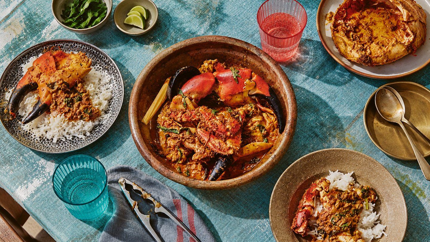An overhead spread of Jaffna crab curry in a clay pot with rice, plated crab and side dishes, Sri Lanka