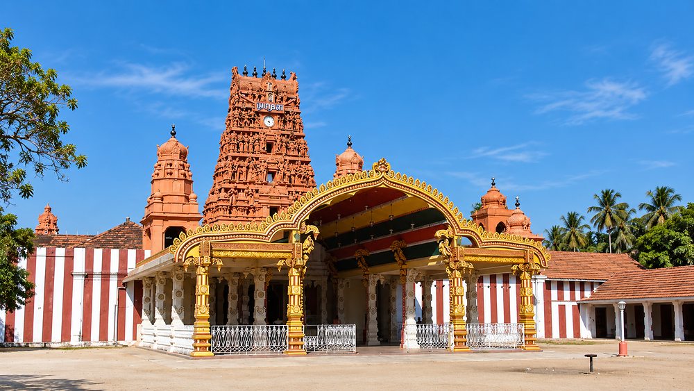 The gold and terracotta gopuram of Nallur Kandaswamy Kovil under a clear sky, Jaffna, Sri Lanka
