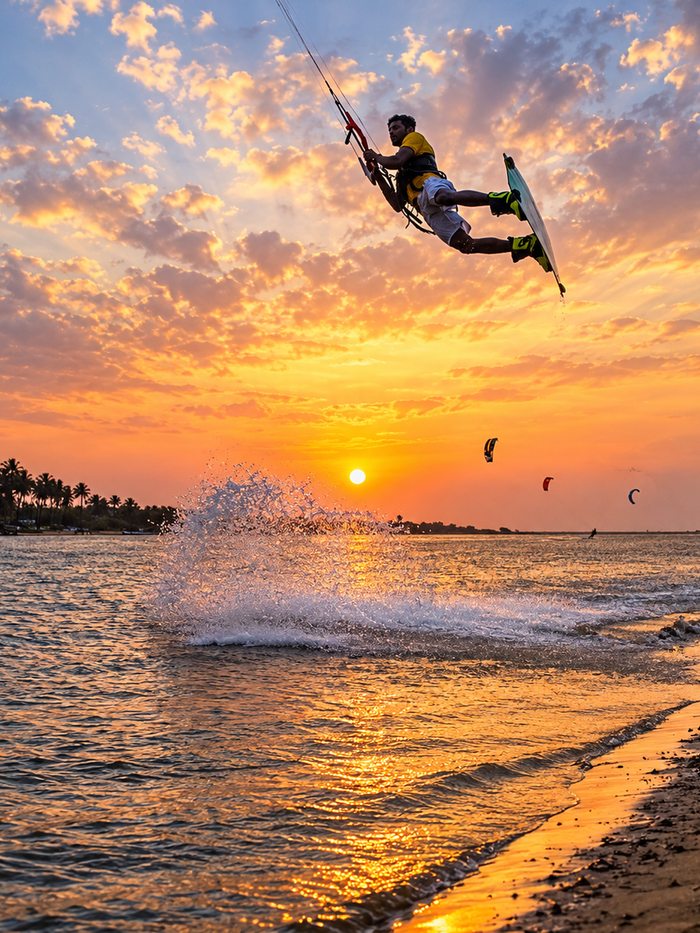 A kitesurfer carving across flat turquoise water off Kalpitiya, Sri Lanka