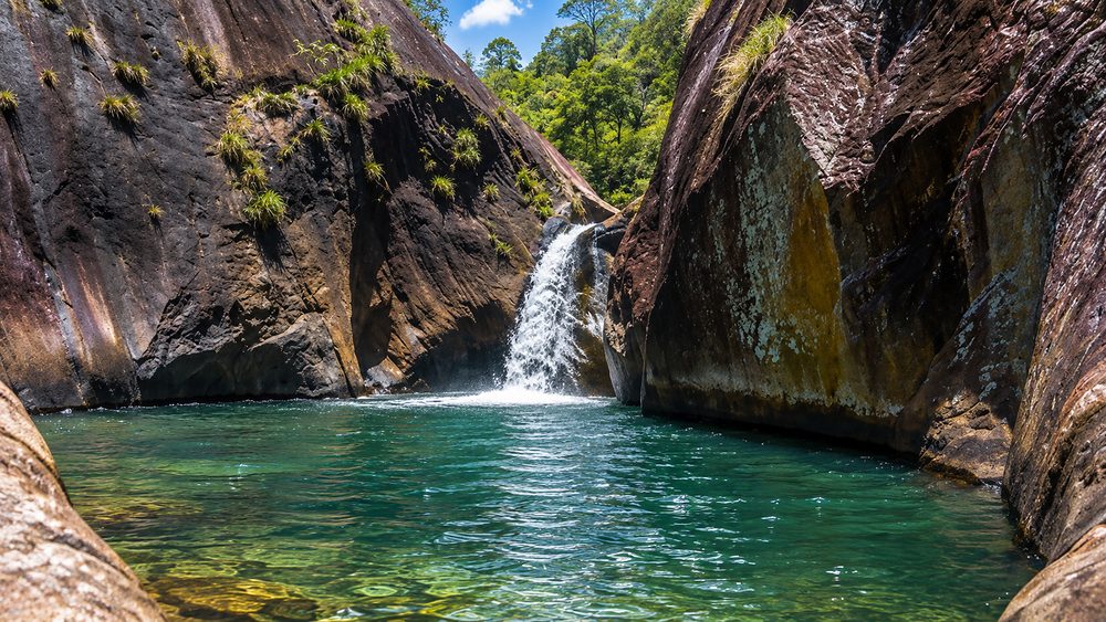 A clear river pool among rocks and forest near Meemure in the Knuckles