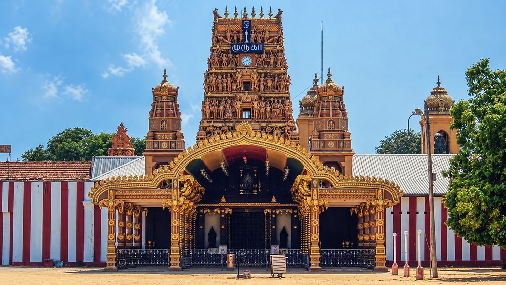 The carved gopuram of Nallur Kandaswamy Kovil above its golden entrance arch, with the temple clock, Jaffna, Sri Lanka