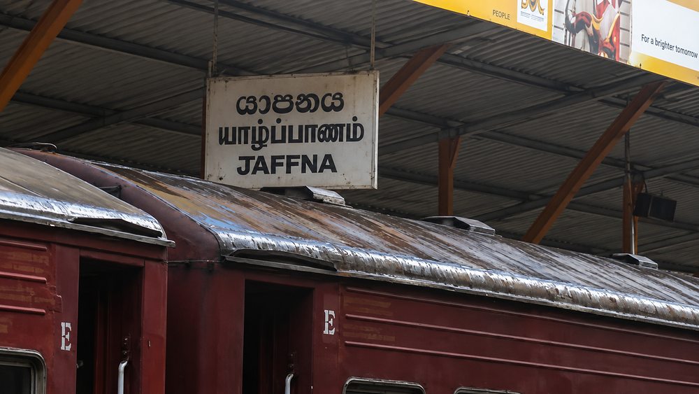 The trilingual Jaffna station sign above a maroon carriage roof, Sri Lanka