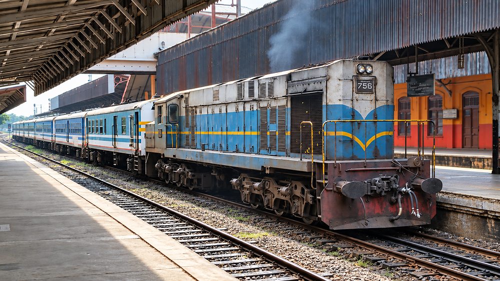 A blue and white Sri Lanka Railways diesel locomotive and carriages waiting at the platform, Sri Lanka