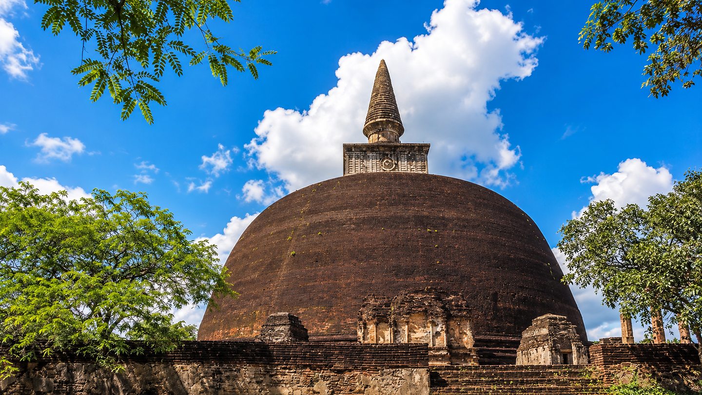 The brick dome and carved spire of the Rankot Vehera stupa against a blue sky, Polonnaruwa, Sri Lanka