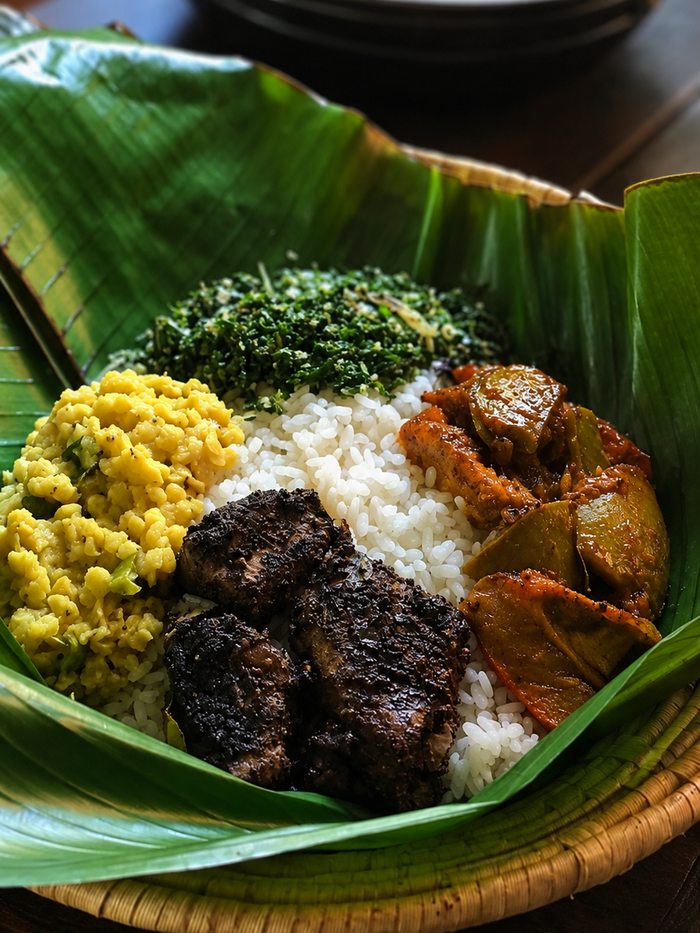 Clay pots of bean curry, cashew curry, dhal and rice with onion sambol on a dark cloth, Sri Lanka