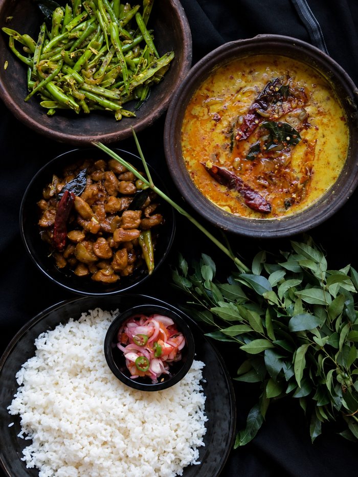A rice and curry spread in clay bowls — yellow rice, dhal, beans, pol sambol and papadum, Sri Lanka
