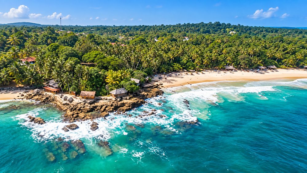 The sheltered cove at Goyambokka from the air, rock outcrops and palms above the sand, Tangalle, Sri Lanka