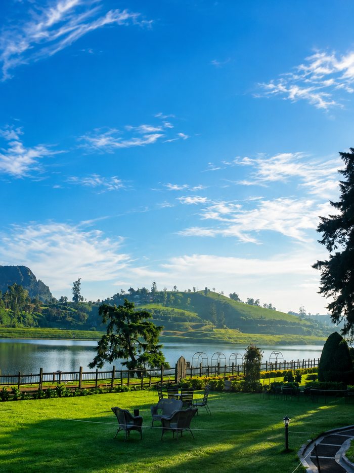 Garden chairs on a lawn above a hill-country lake at Nuwara Eliya, Sri Lanka
